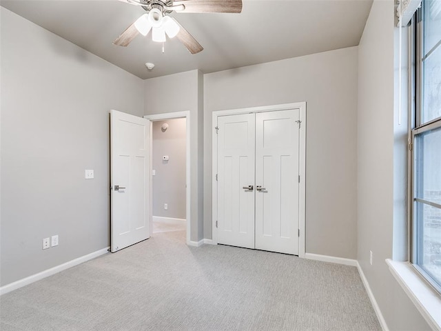 unfurnished bedroom featuring multiple windows, a closet, ceiling fan, and light carpet