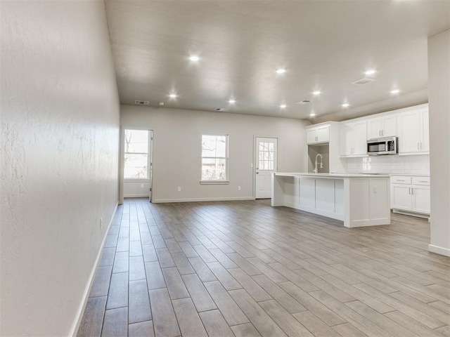 unfurnished living room with sink and light hardwood / wood-style floors