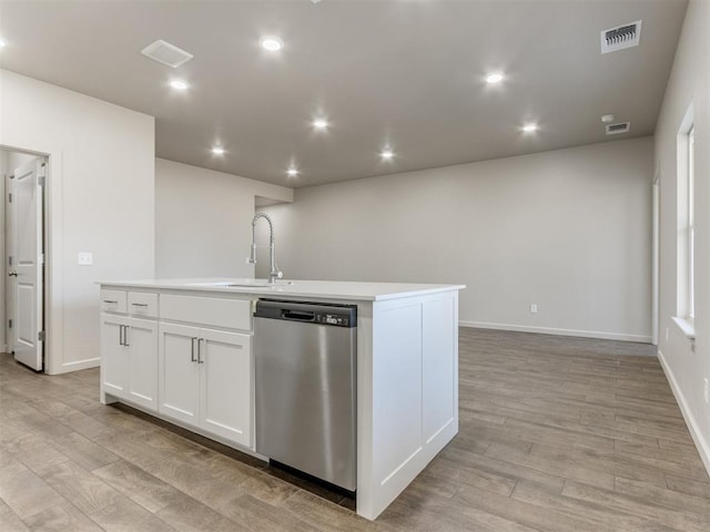 kitchen with sink, white cabinets, stainless steel dishwasher, a center island with sink, and light hardwood / wood-style flooring