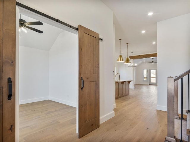 corridor featuring a barn door, recessed lighting, baseboards, stairs, and light wood finished floors