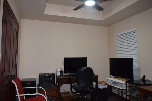 office area with a raised ceiling and ceiling fan