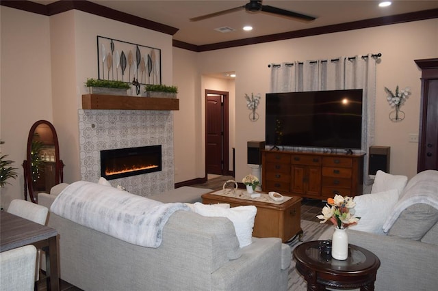 living room with crown molding, a tile fireplace, and ceiling fan