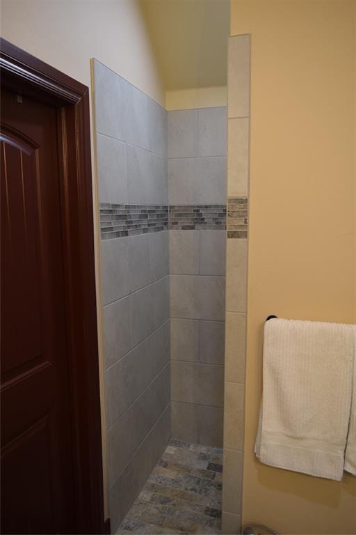 bathroom featuring tiled shower and lofted ceiling