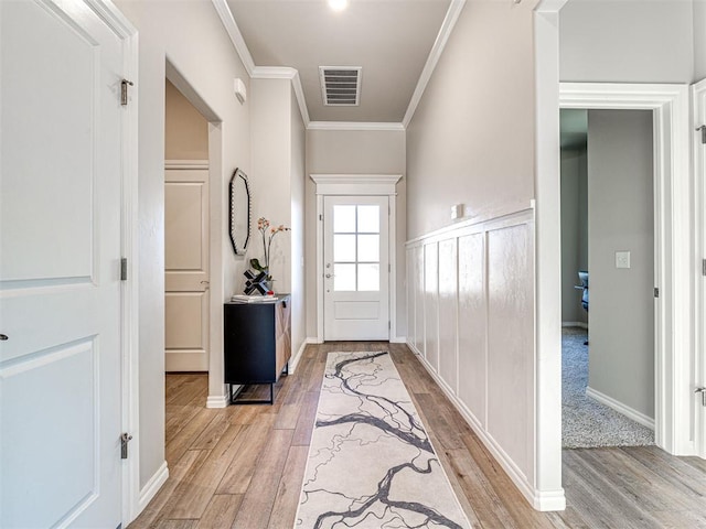 doorway featuring crown molding and light hardwood / wood-style floors