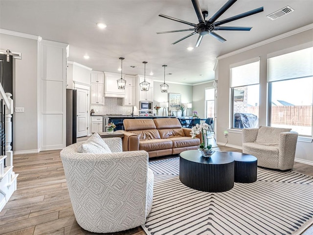 living room featuring ornamental molding, light hardwood / wood-style floors, a barn door, and ceiling fan