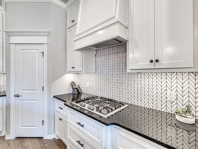 kitchen featuring white cabinetry, stainless steel gas cooktop, dark stone countertops, and decorative backsplash