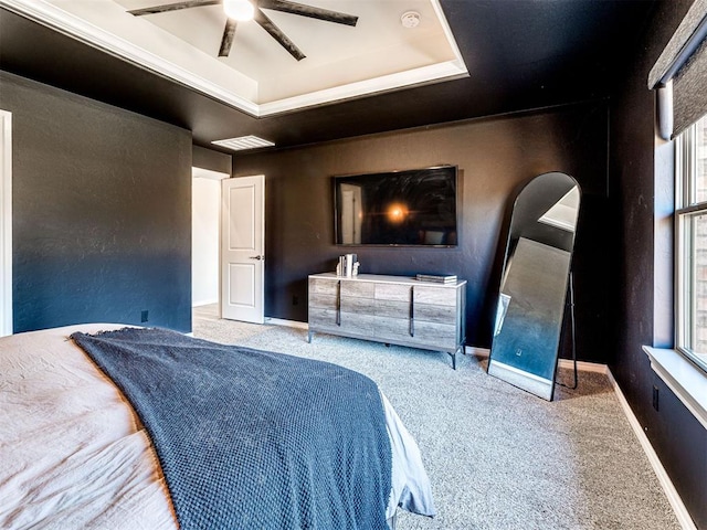 bedroom with carpet floors, ceiling fan, and a tray ceiling