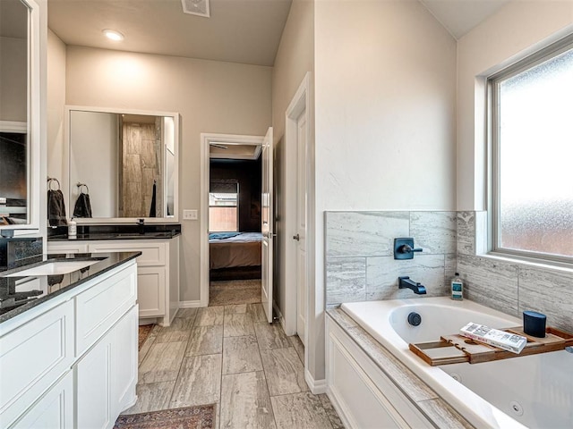 bathroom with vanity, a wealth of natural light, and a bathtub