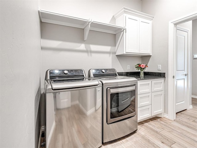 washroom featuring separate washer and dryer, cabinets, and light wood-type flooring