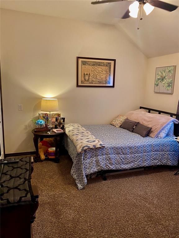 carpeted bedroom with ceiling fan and vaulted ceiling