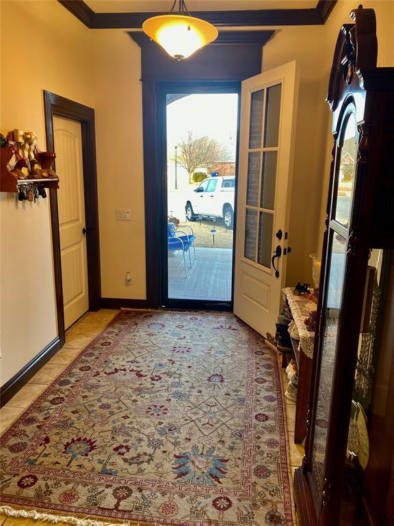 entryway featuring ornamental molding and light tile patterned floors