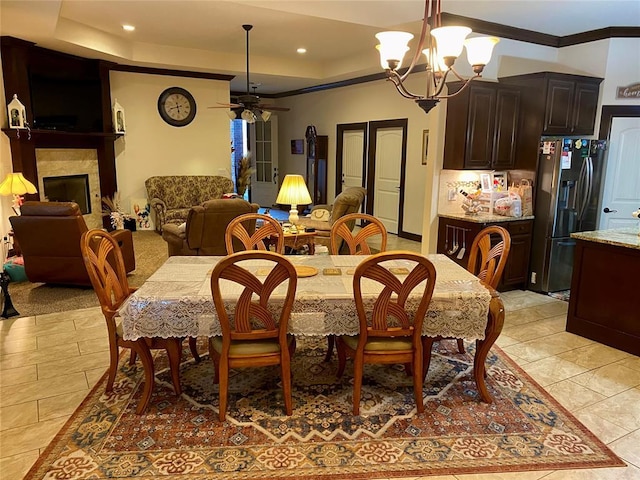 dining area with a raised ceiling, ornamental molding, and ceiling fan with notable chandelier