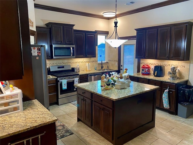 kitchen featuring appliances with stainless steel finishes, sink, hanging light fixtures, ornamental molding, and a center island