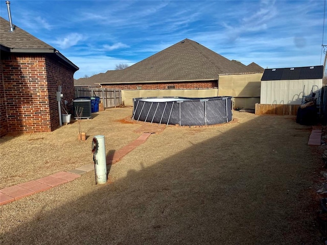 view of yard with a shed, a covered pool, and central air condition unit