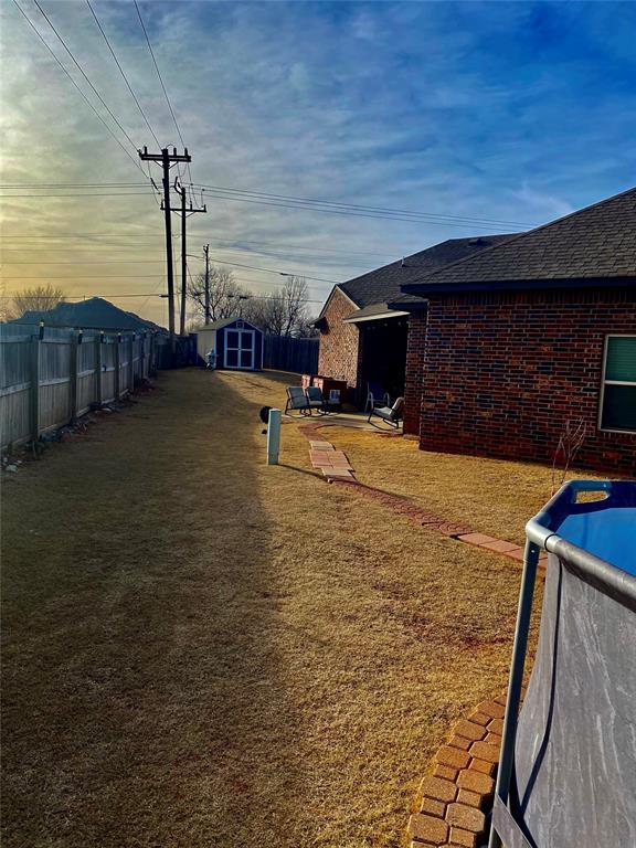 yard at dusk with a shed and a fenced in pool