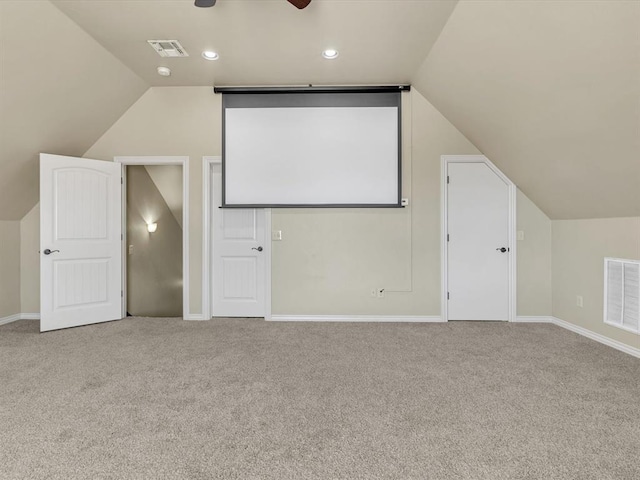 carpeted cinema room featuring vaulted ceiling, baseboards, visible vents, and a ceiling fan