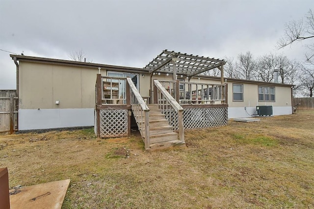 back of property with a wooden deck, a pergola, a lawn, and central AC