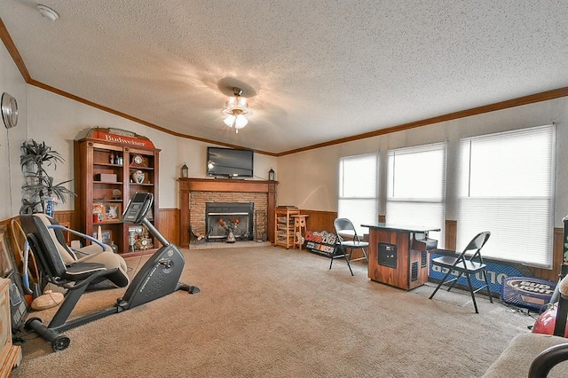 living room with a brick fireplace, a textured ceiling, ornamental molding, wooden walls, and carpet flooring