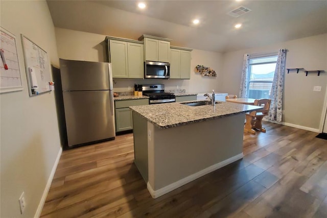 kitchen featuring a center island with sink, visible vents, appliances with stainless steel finishes, light stone countertops, and a sink