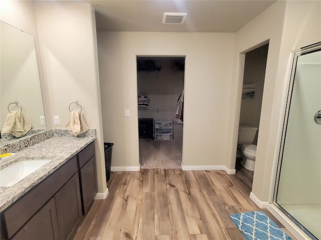 full bath with wood finished floors, vanity, visible vents, a spacious closet, and a stall shower