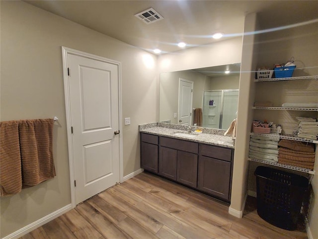 full bathroom with wood finished floors, vanity, visible vents, baseboards, and a stall shower