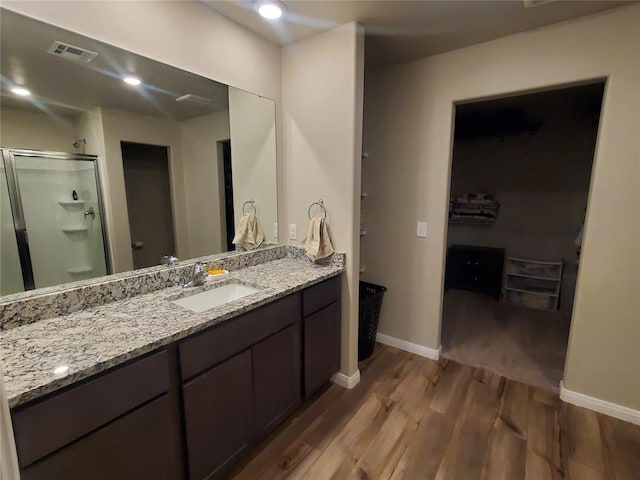 bathroom with visible vents, a shower stall, vanity, wood finished floors, and baseboards