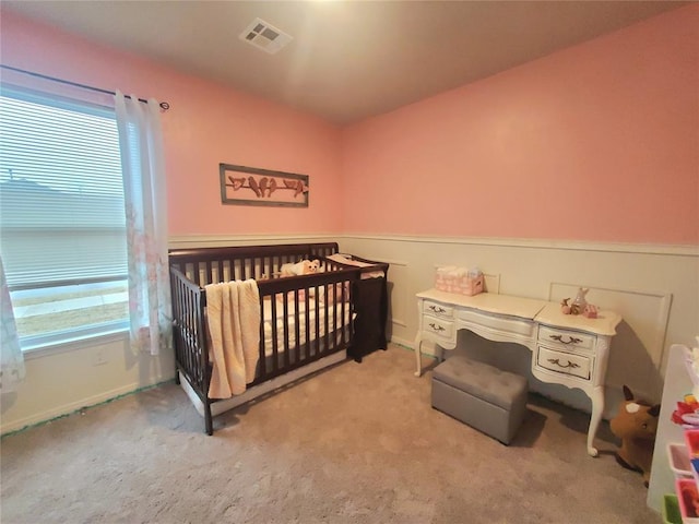 bedroom with visible vents, light carpet, baseboards, and a crib