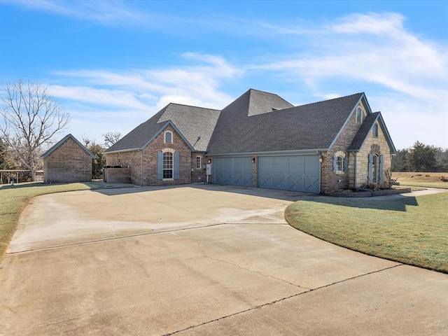 view of front facade featuring a shingled roof, a front yard, brick siding, and driveway