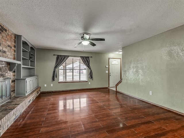 unfurnished living room featuring built in features, a fireplace, ceiling fan, dark wood-type flooring, and a textured ceiling