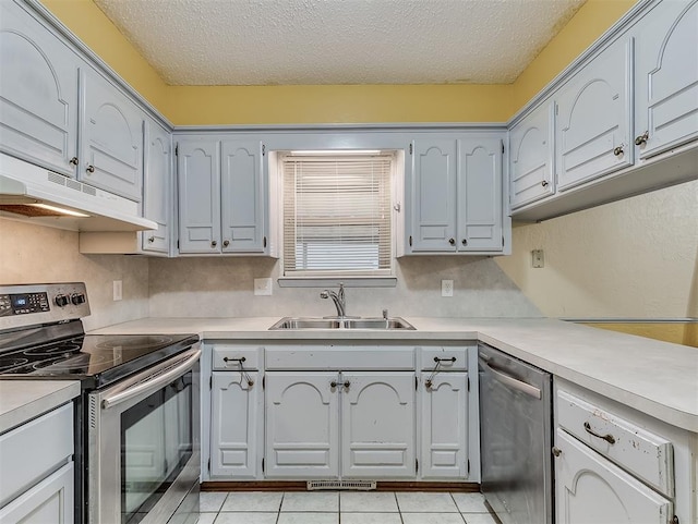 kitchen featuring light tile patterned flooring, sink, backsplash, stainless steel appliances, and a textured ceiling