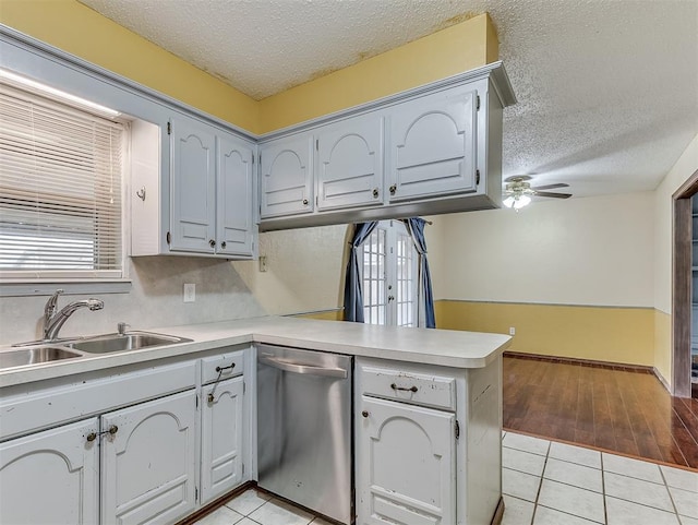 kitchen with dishwasher, sink, gray cabinetry, light tile patterned floors, and kitchen peninsula