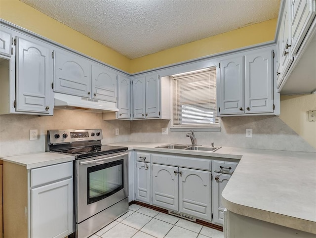 kitchen with sink, stainless steel range with electric cooktop, decorative backsplash, light tile patterned floors, and a textured ceiling