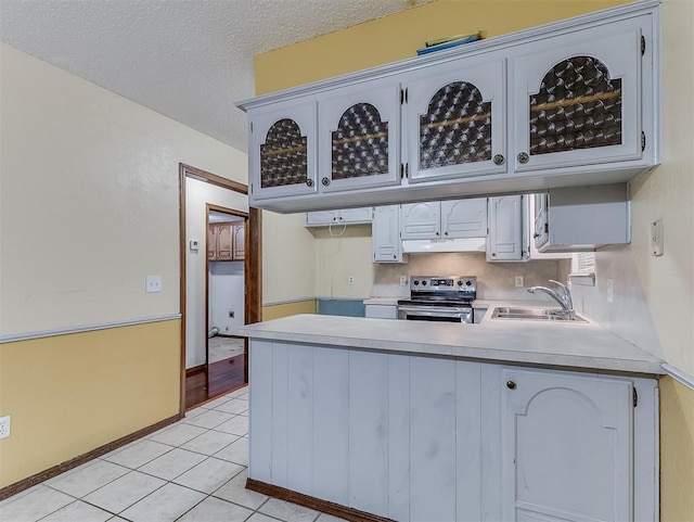 kitchen with sink, white cabinets, light tile patterned flooring, stainless steel range with electric cooktop, and kitchen peninsula