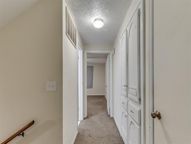 corridor featuring light colored carpet and a textured ceiling