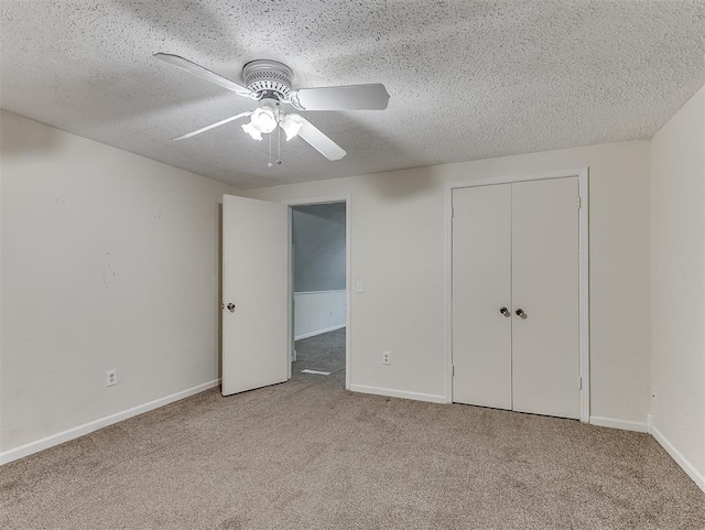 unfurnished bedroom featuring light carpet, ceiling fan, a closet, and a textured ceiling