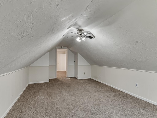 bonus room featuring ceiling fan, carpet flooring, vaulted ceiling, and a textured ceiling