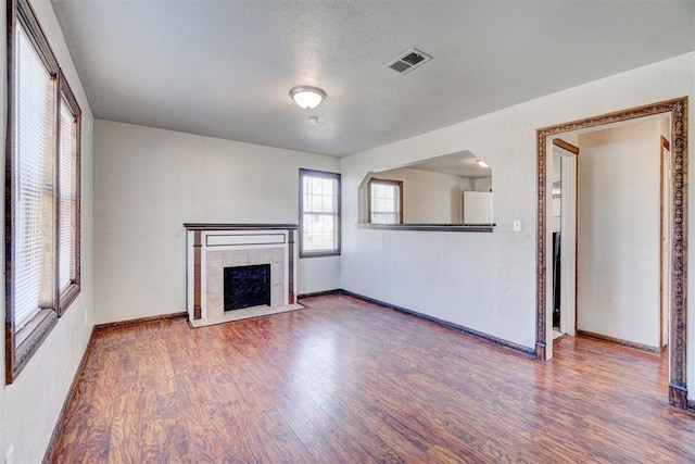 unfurnished living room with hardwood / wood-style flooring and a tile fireplace