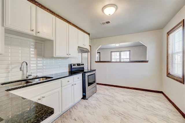 kitchen featuring sink, dark stone countertops, white cabinets, electric range, and a healthy amount of sunlight