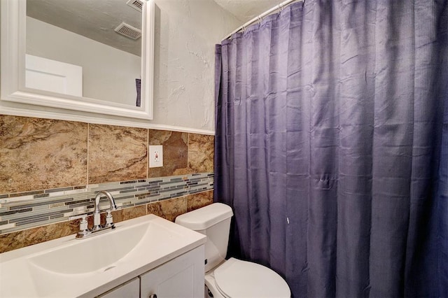 bathroom featuring vanity, toilet, and tile walls