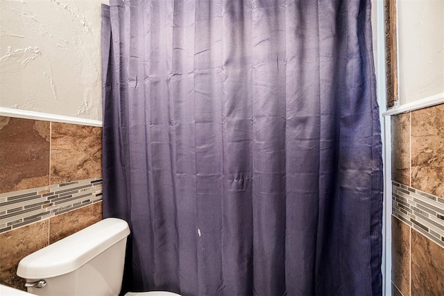 bathroom with tile walls and toilet