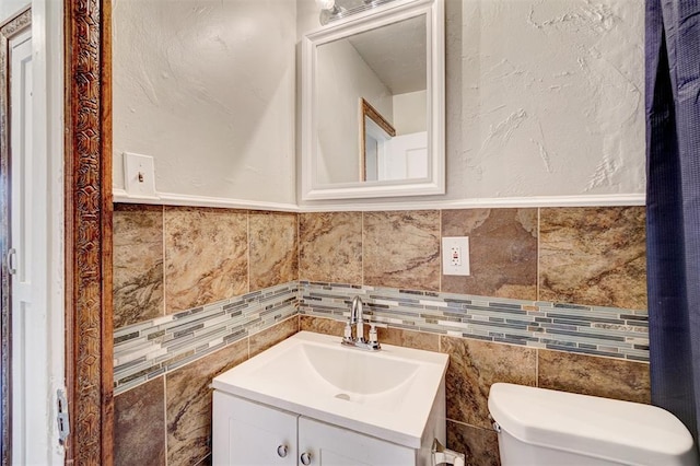 bathroom with vanity, toilet, and tile walls