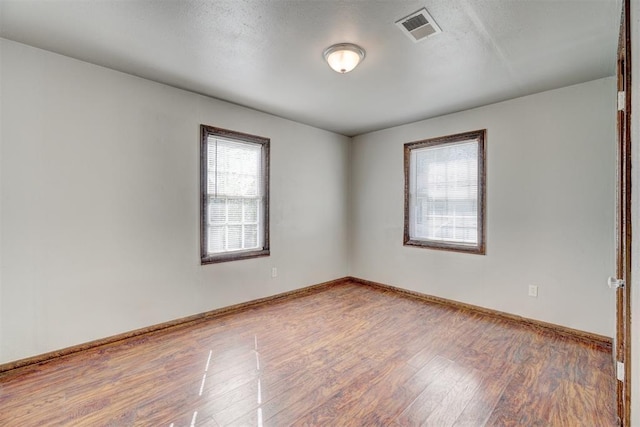 unfurnished room with hardwood / wood-style flooring and a textured ceiling