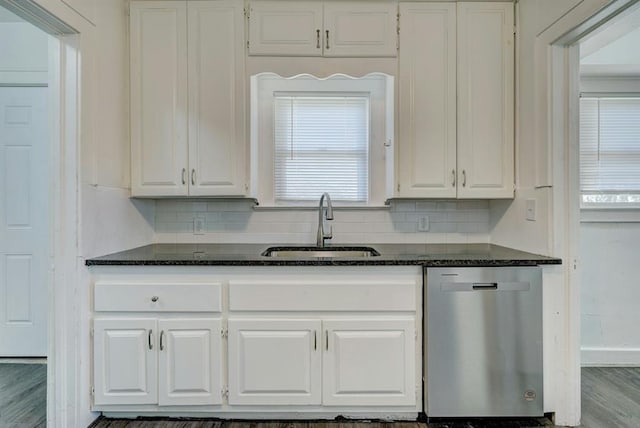 kitchen with sink, stainless steel dishwasher, dark stone counters, and white cabinets