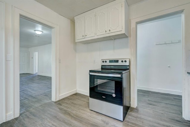 kitchen with electric stove, white cabinetry, and light hardwood / wood-style floors