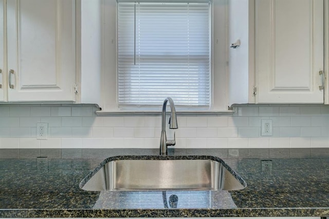 kitchen featuring white cabinetry, dark stone counters, sink, and tasteful backsplash