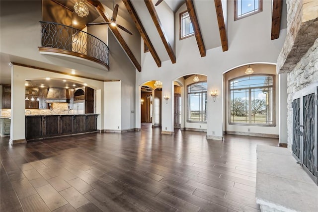 unfurnished living room with beamed ceiling, dark hardwood / wood-style floors, and high vaulted ceiling