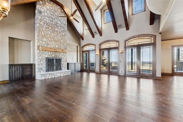 unfurnished living room featuring beam ceiling, a stone fireplace, ceiling fan, and hardwood / wood-style flooring