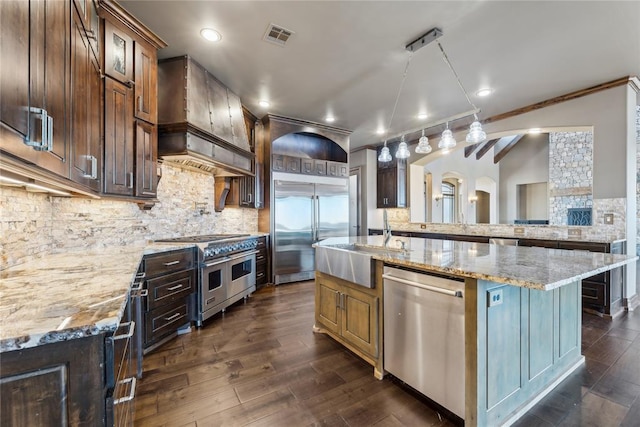 kitchen featuring tasteful backsplash, premium appliances, light stone countertops, dark brown cabinets, and a spacious island