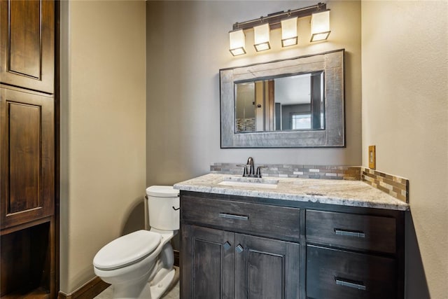 bathroom featuring vanity, toilet, and backsplash