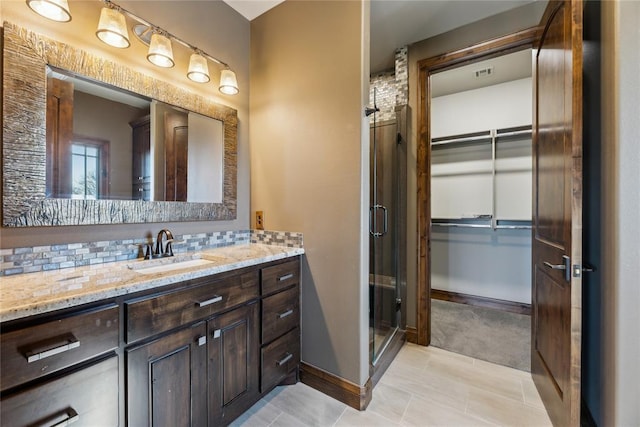 bathroom featuring vanity, backsplash, and walk in shower